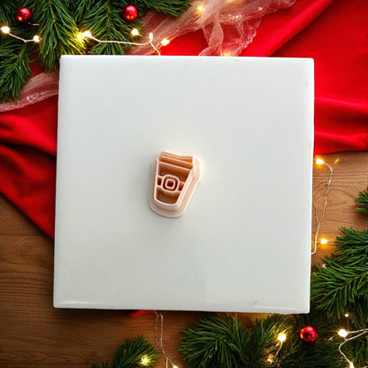 Santa coffee cup cutter on red napkin with pine greenery and Christmas lights