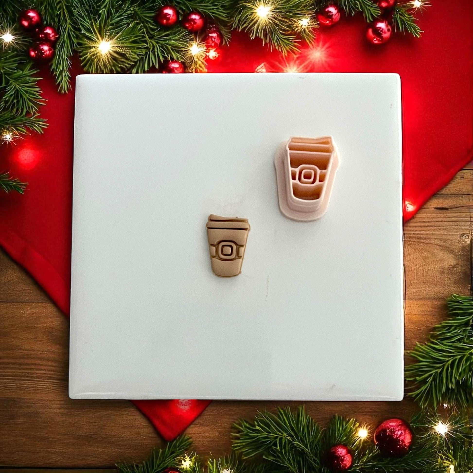 Coffee cup polymer clay cutter close-up on white tile with lights and red background