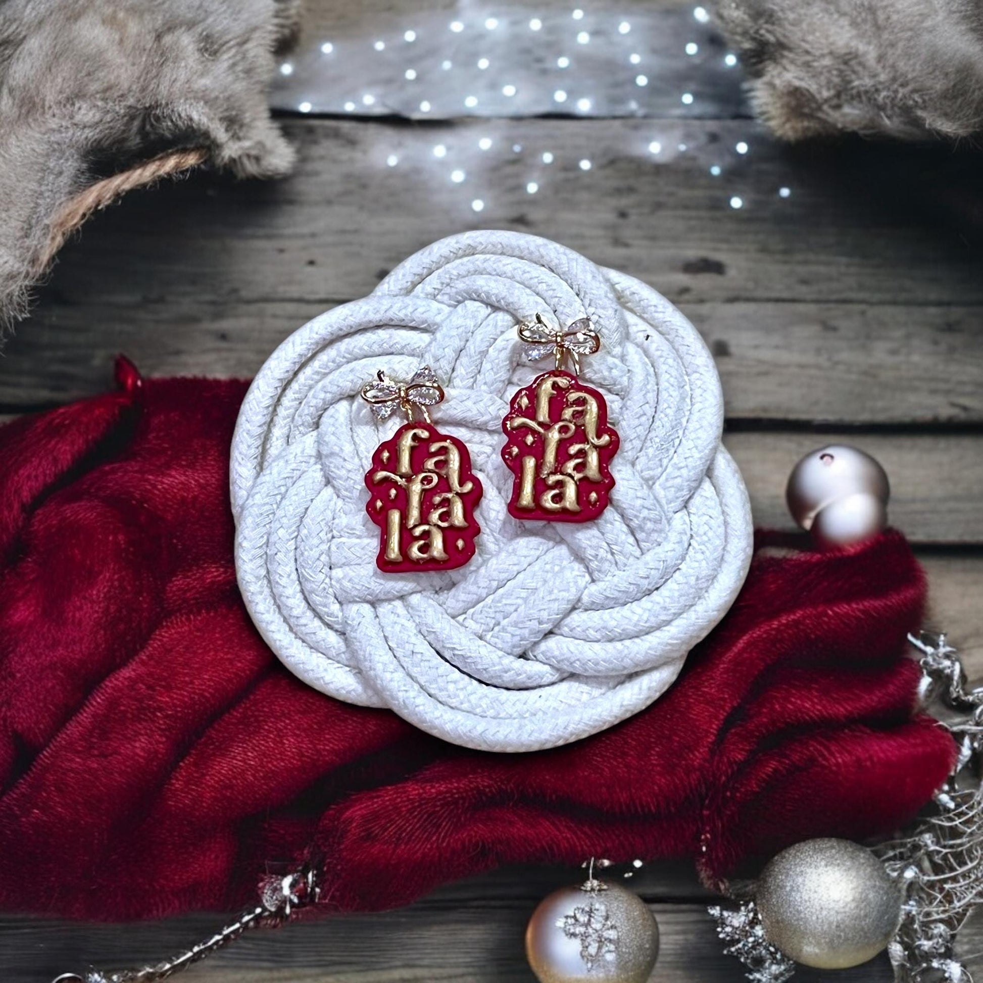 Red and gold Fa La La polymer clay earrings with bows styled on holiday background