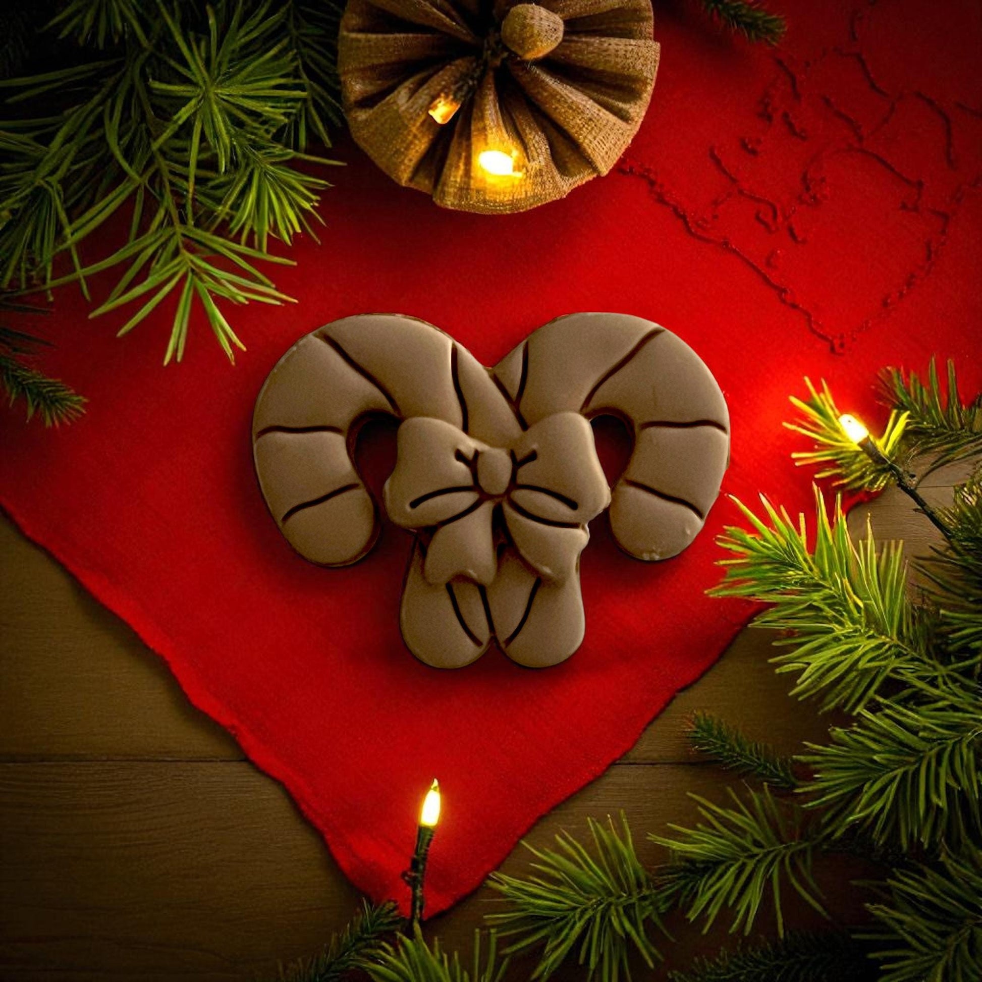 Candy cane bow polymer clay cutters displayed on red fabric with pine branches and ornaments