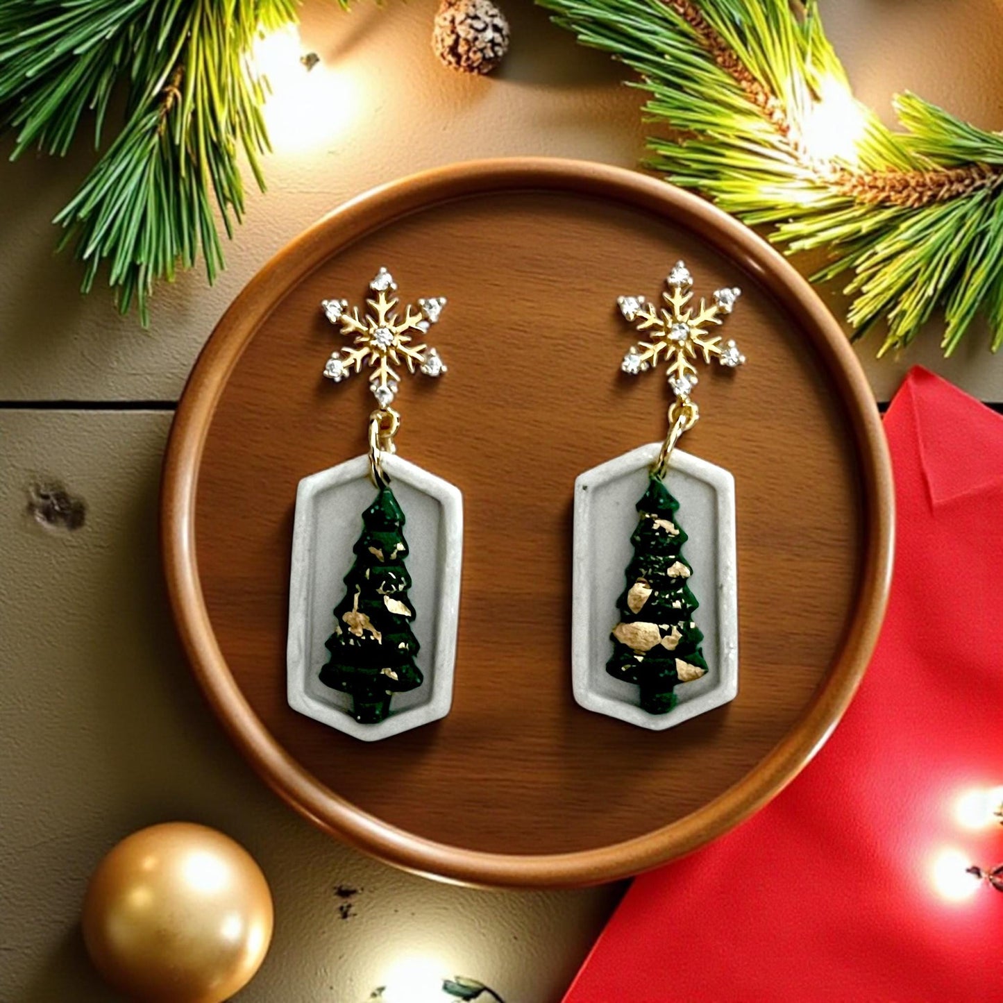 Green Christmas tree earrings inside geometric white frame with gold snowflake toppers