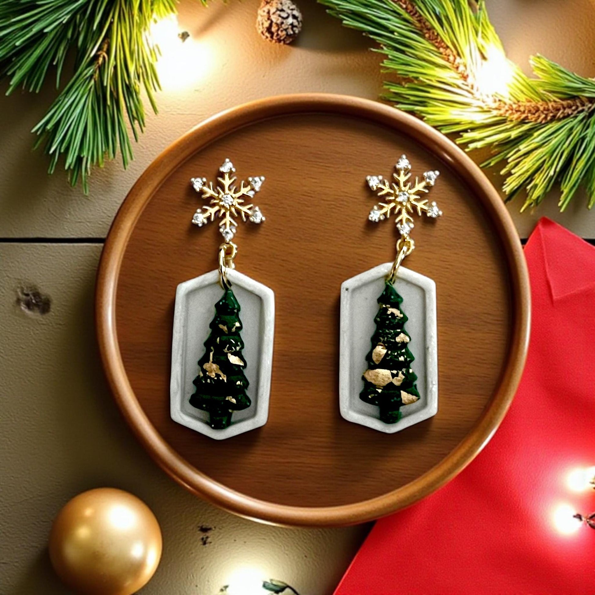 Green Christmas tree earrings inside geometric white frame with gold snowflake toppers