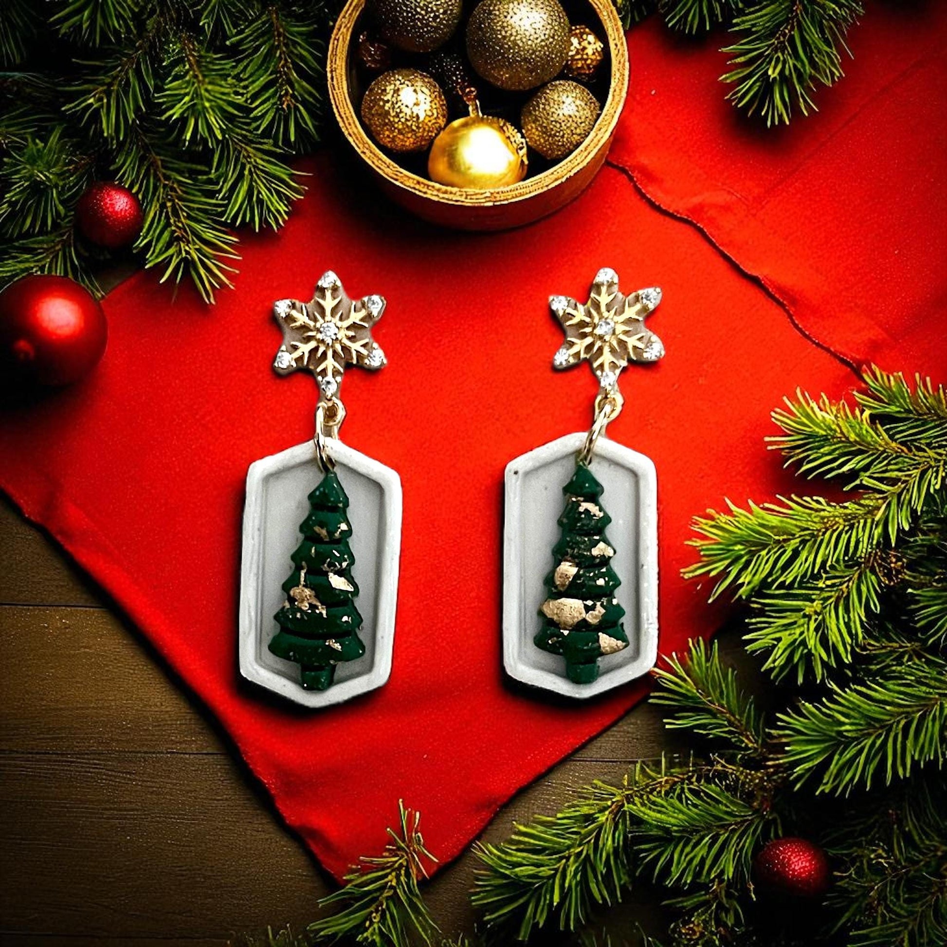 Green Christmas tree earrings inside geometric white frame with gold snowflake toppers