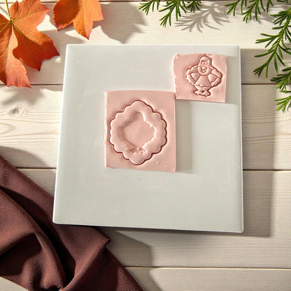 Pilgrim turkey clay imprint inside scalloped frame on white tile with fall leaves
