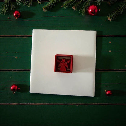 Red angel square cutter centered on white tile with Christmas ornaments
