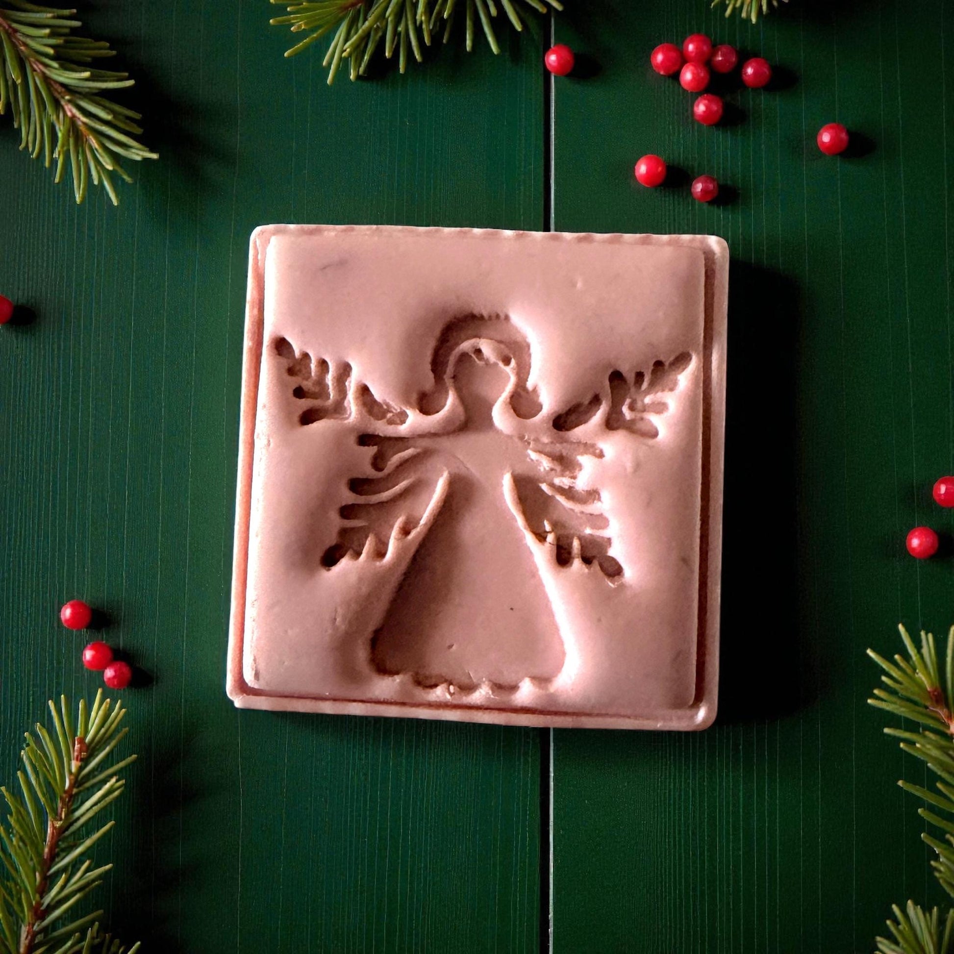 Close-up of angel clay imprint showing wing details on green wood background