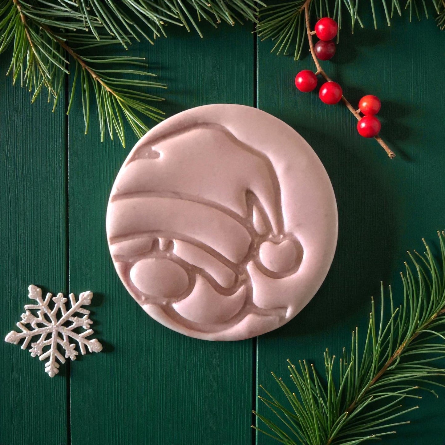 Close-up of Santa clay imprint showing hat and nose details on green wood background