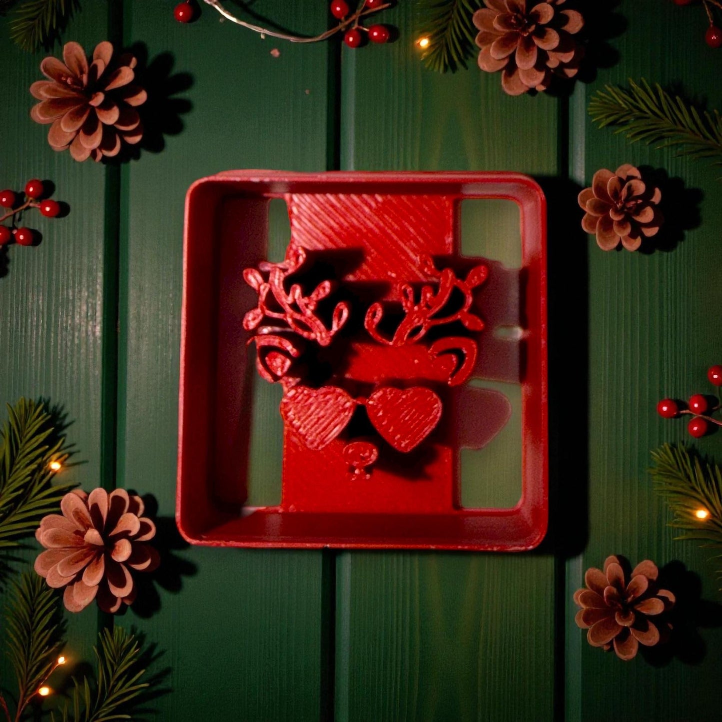 Close-up of red reindeer cutter surrounded by pinecones and Christmas lights