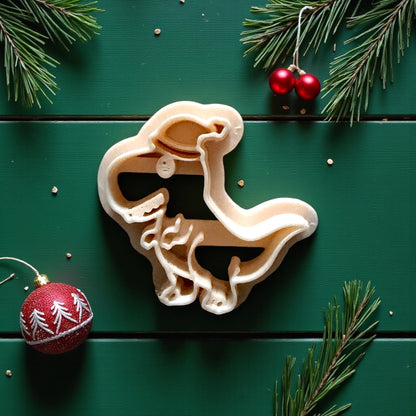 Close-up of cream dino cutter with Santa hat surrounded by pine branches and ornaments