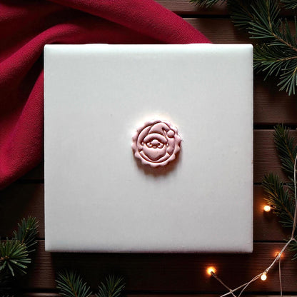 Centered pink Santa imprint on wood background with greenery and red fabric