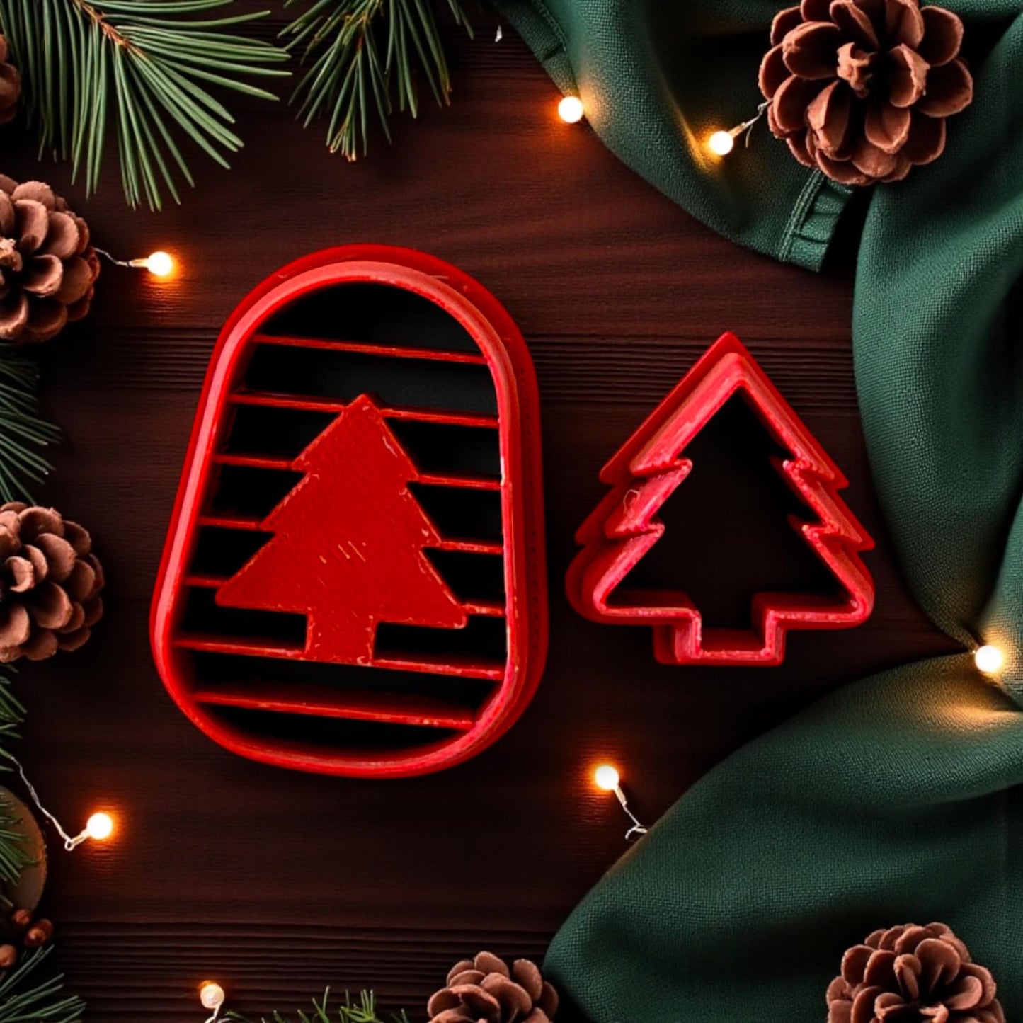 Red arched cutter and tree cutter surrounded by pinecones, green fabric, and holiday lights