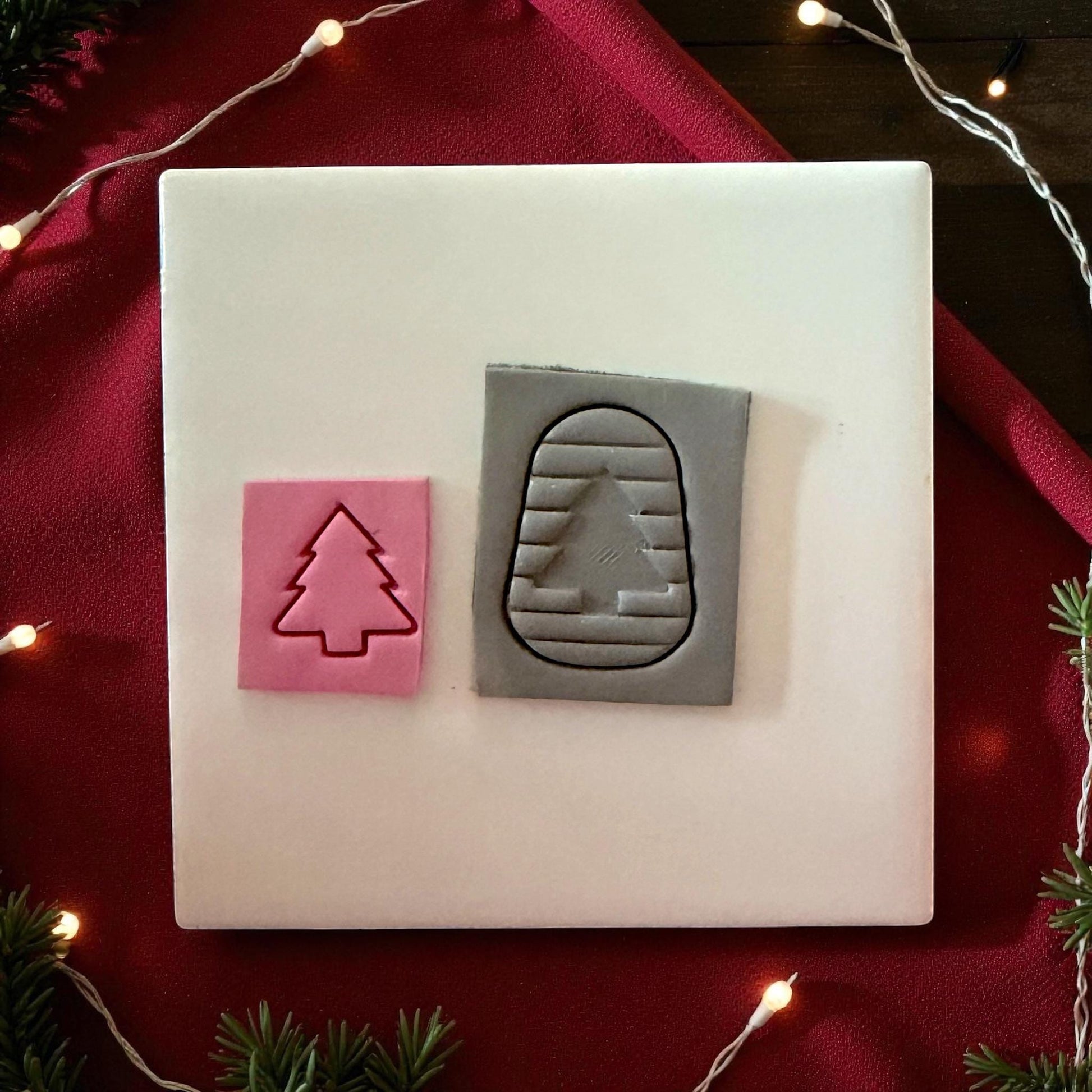Pink tree clay imprint inside gray arched clay piece with red twine and greenery
