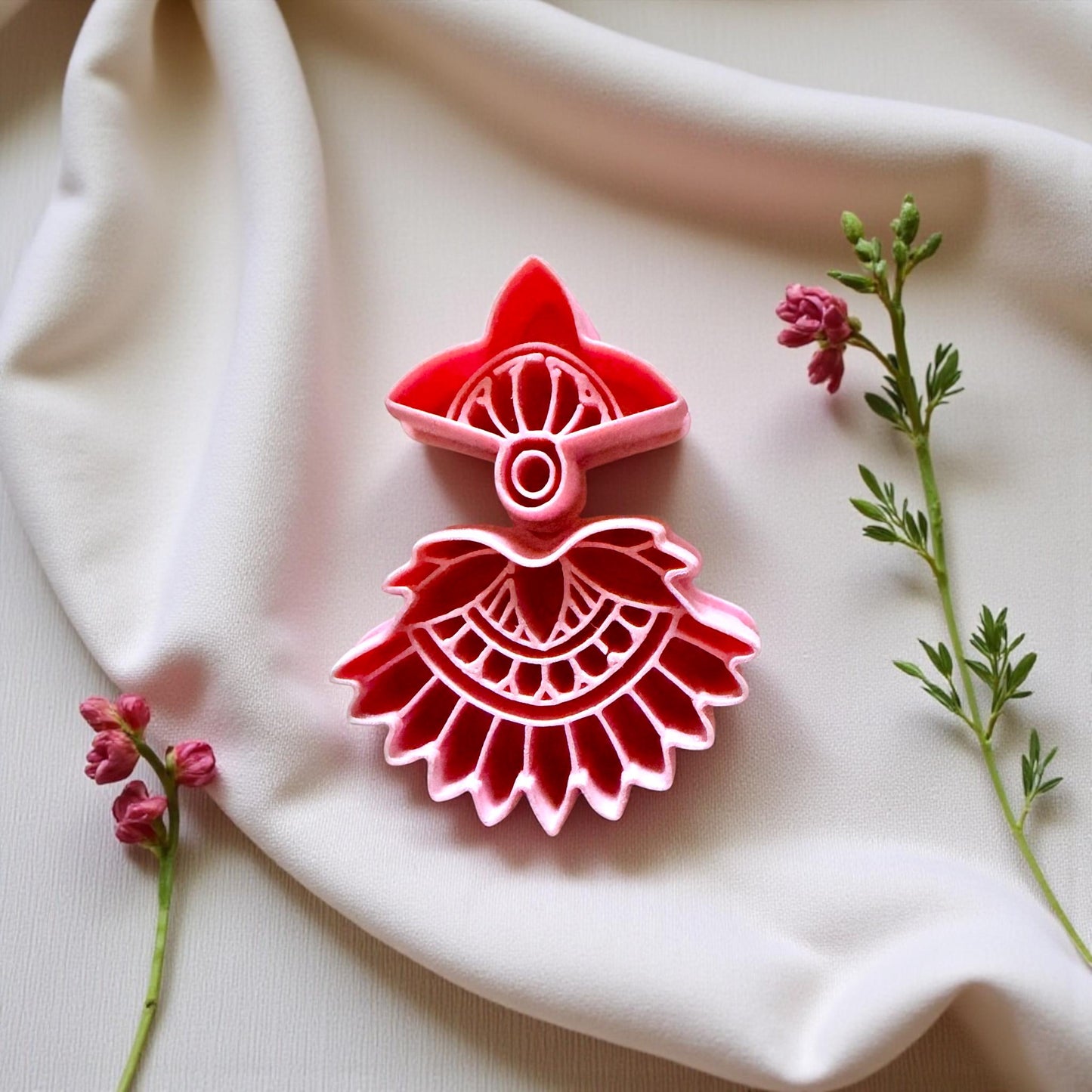 Close-up of red boho fan cutter on cream fabric with tiny pink flowers