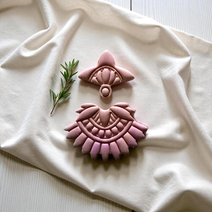 Close-up of pink clay boho fan pieces on ivory cloth with greenery