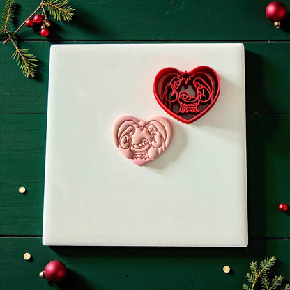 Heart nativity cutter and pink clay imprint on white tile surrounded by Christmas accents