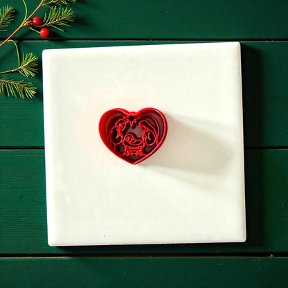 Heart nativity cutter centered on white tile with green wooden background and holiday decor