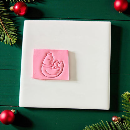 Pink chicken family clay imprint on white tile surrounded by red ornaments