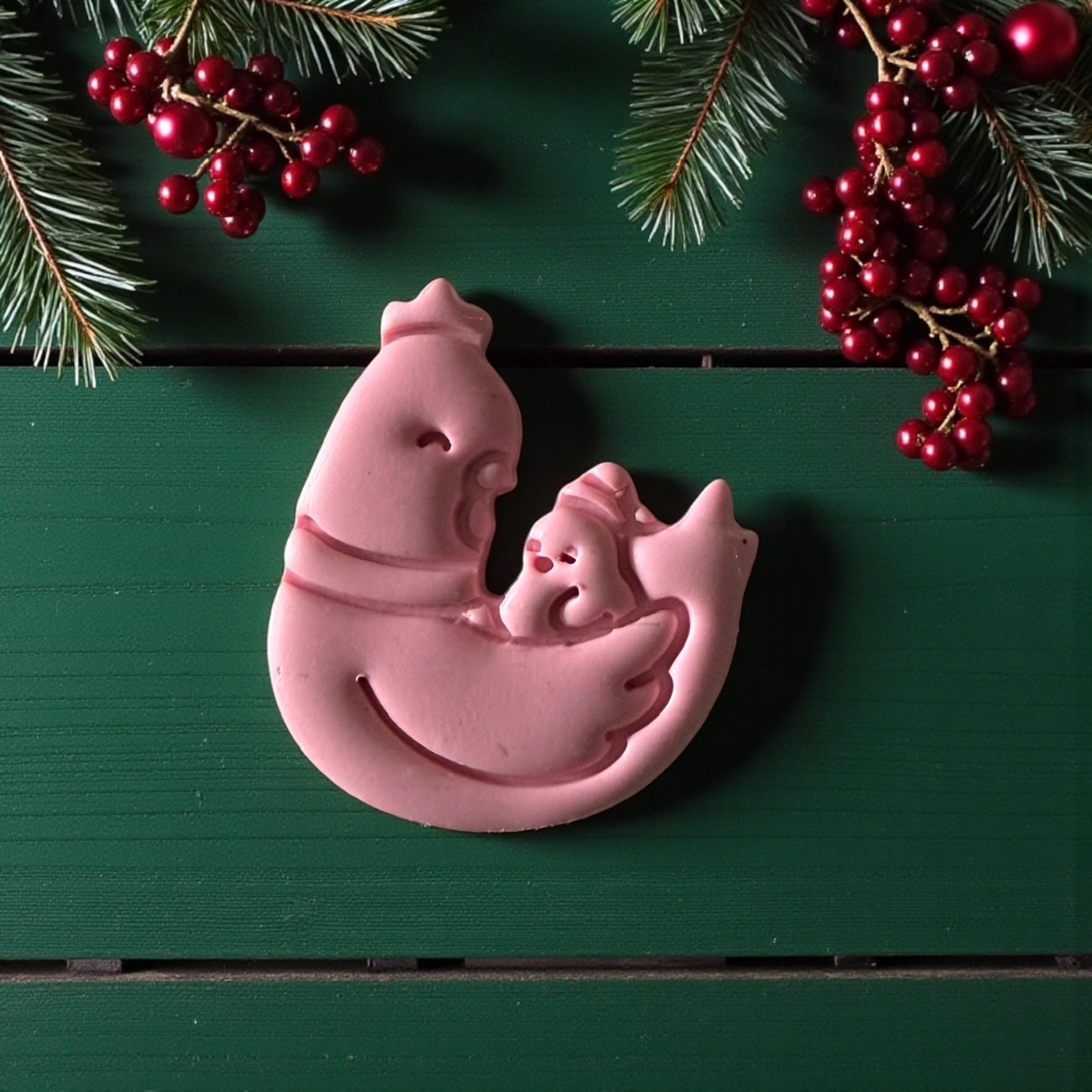 Close-up of pink mother hen and chick clay imprint with berries and pine branches