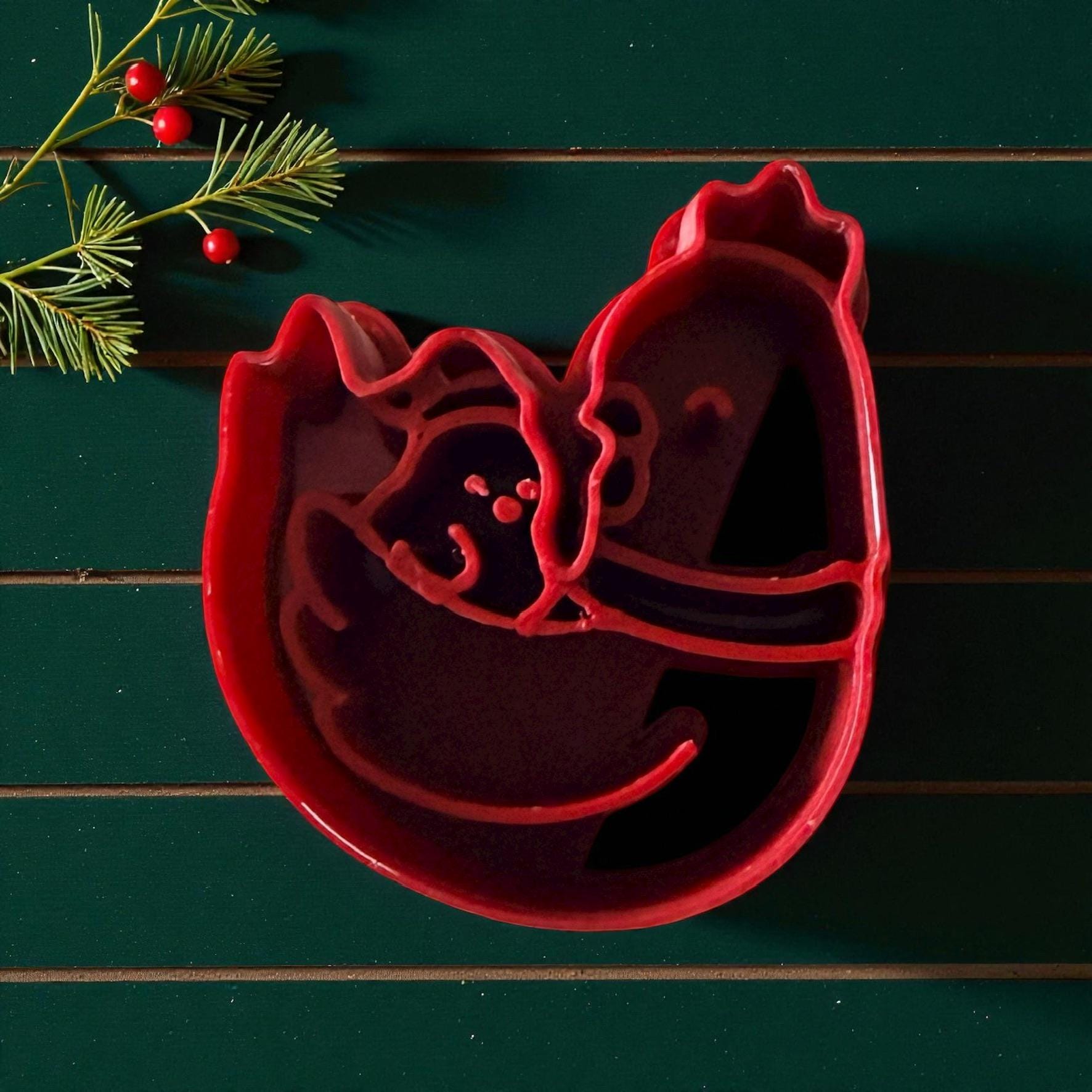 Red chicken and chick polymer clay cutter on green background with pine and berries