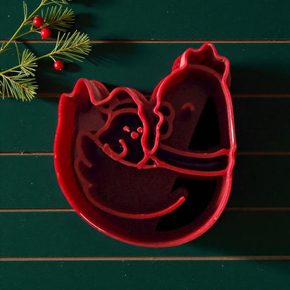 Red chicken and chick polymer clay cutter on green background with pine and berries