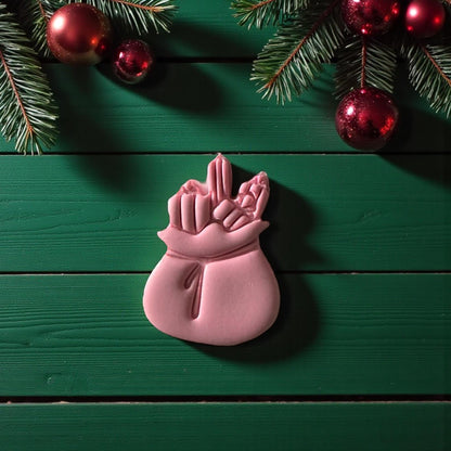 Pink Santa sack imprint centered on white tile surrounded by festive greenery
