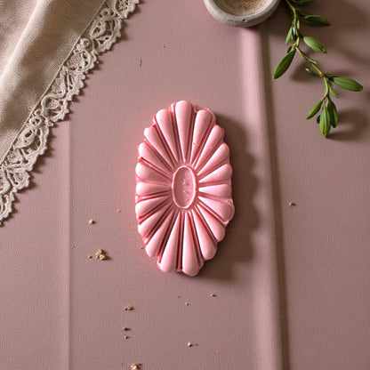 Oval flower cutter and matching clay imprint beside linen cloth and eucalyptus stem