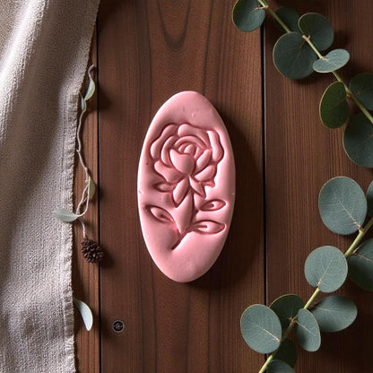 Pink rose clay imprint displayed vertically on wood with eucalyptus leaves and linen fabric