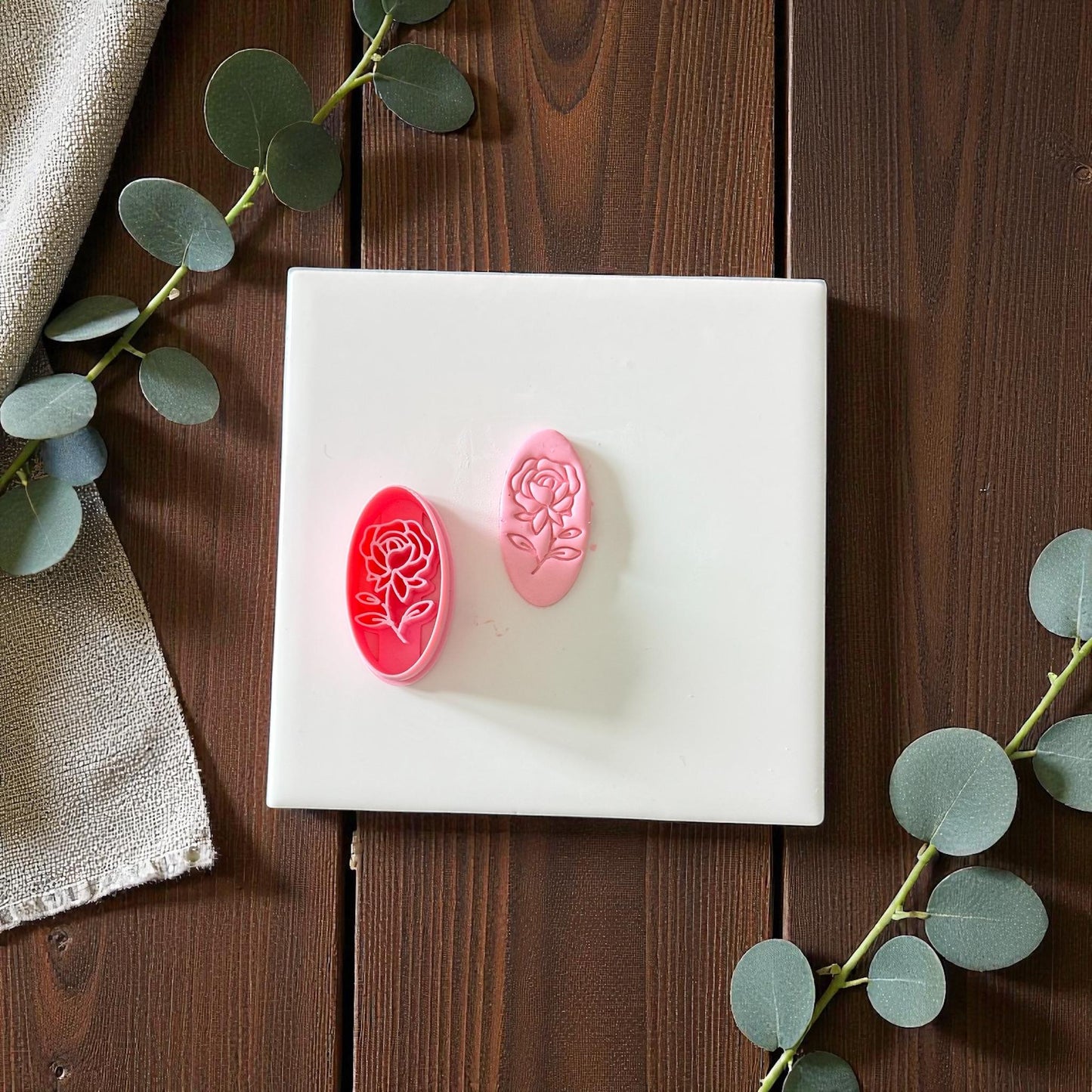 Pink rose oval cutter and imprint on white tile with eucalyptus branches