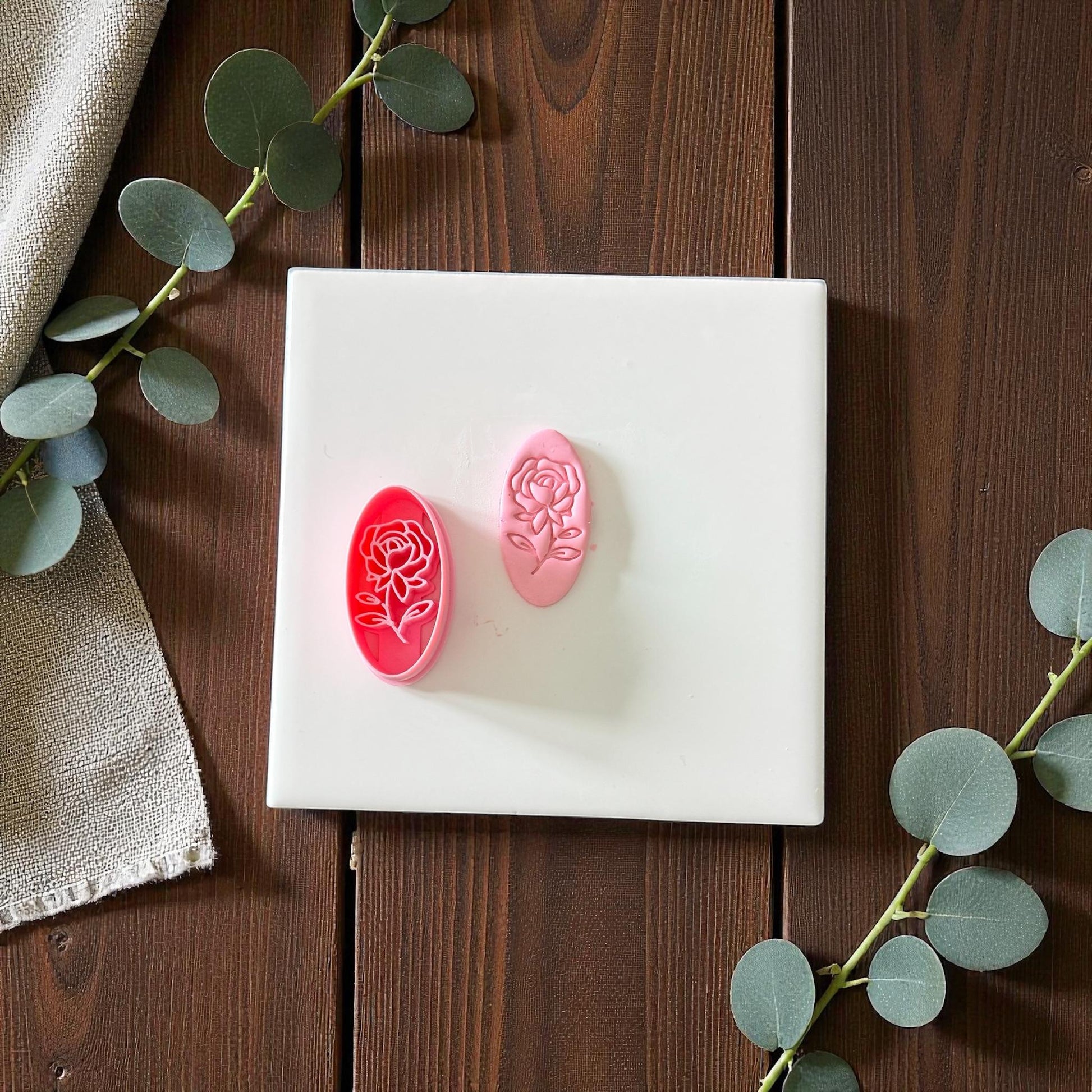 Pink rose oval cutter and imprint on white tile with eucalyptus branches