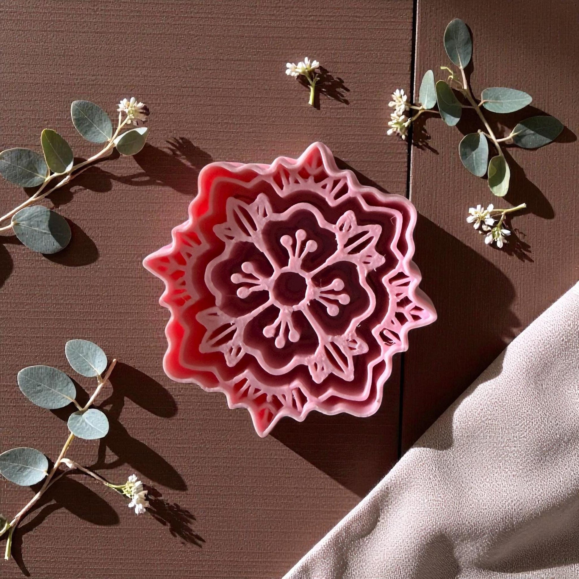 Pink boho floral polymer clay cutter on brown surface with eucalyptus and white flowers