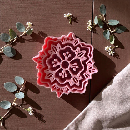 Pink boho floral polymer clay cutter on brown surface with eucalyptus and white flowers