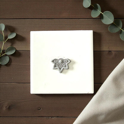 Gray lotus clay imprint on white tile with eucalyptus