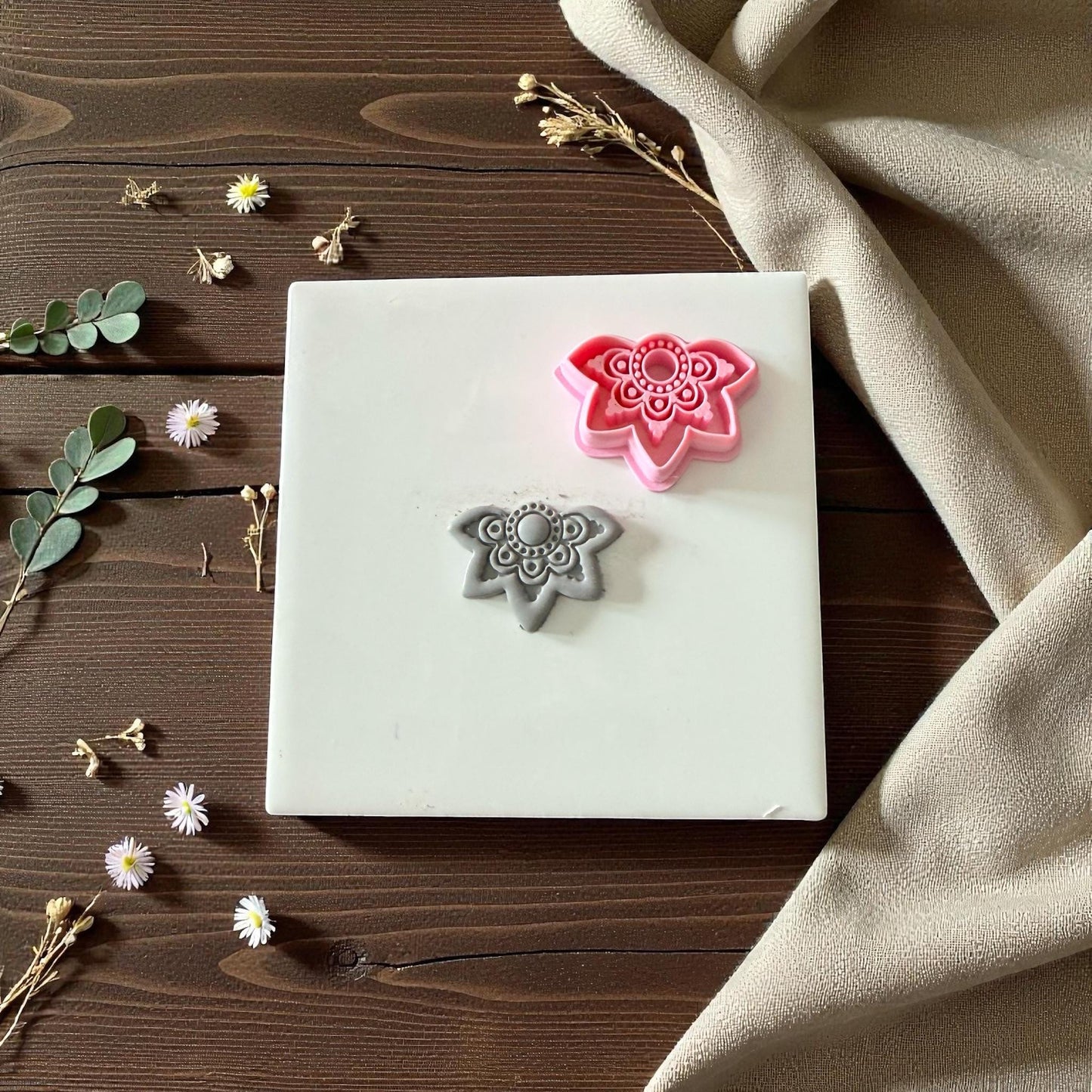 Pink and gray lotus clay cutters with floral imprint on white tile