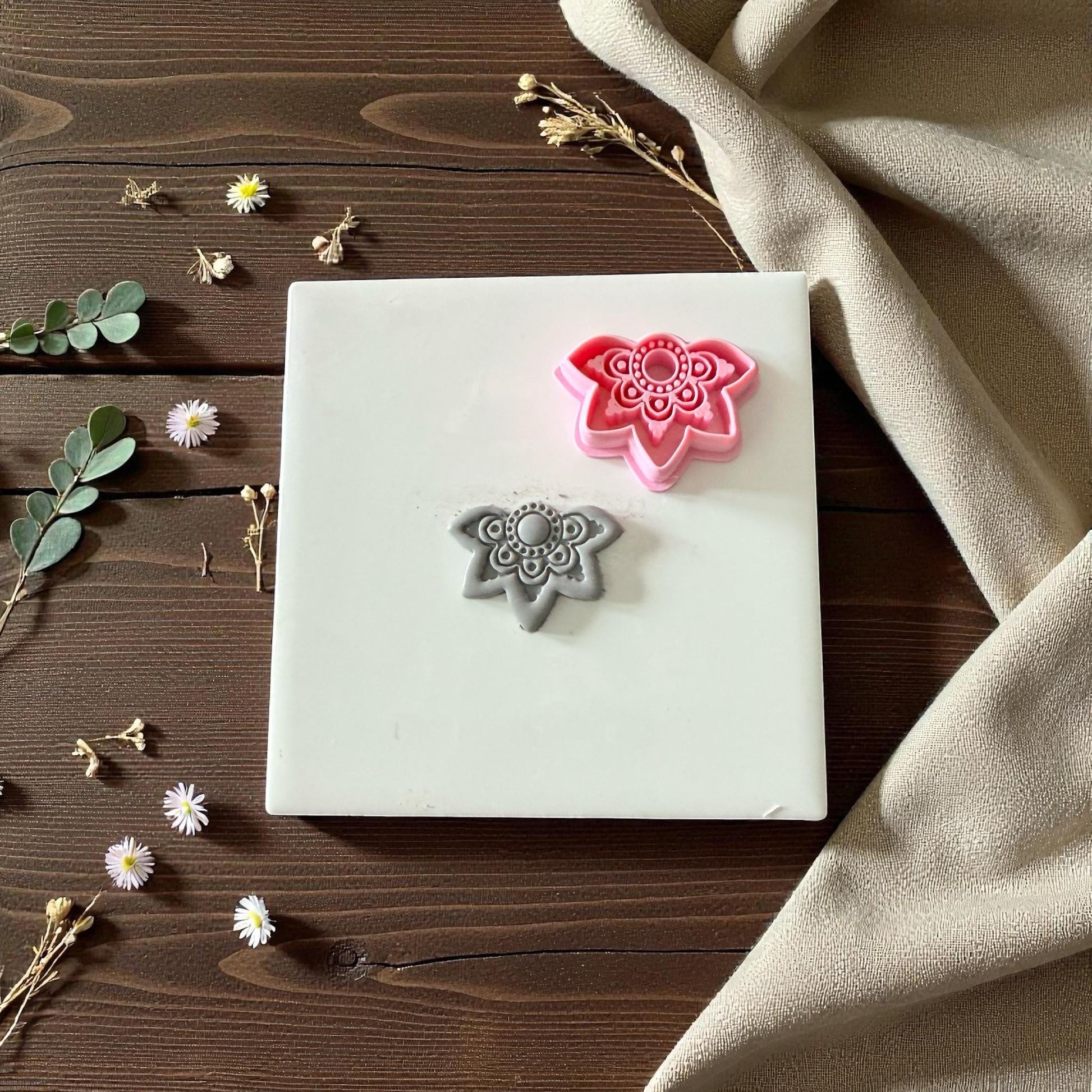 Pink and gray lotus clay cutters with floral imprint on white tile