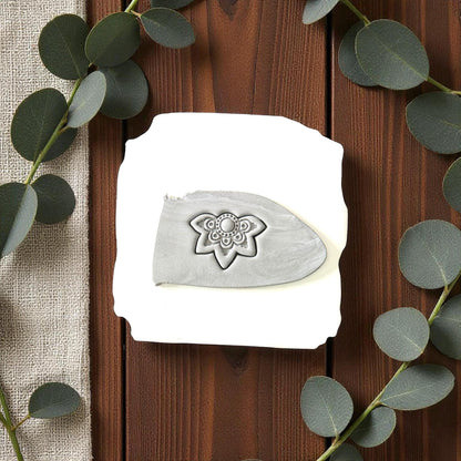 Gray boho flower imprint on clay slab surrounded by eucalyptus