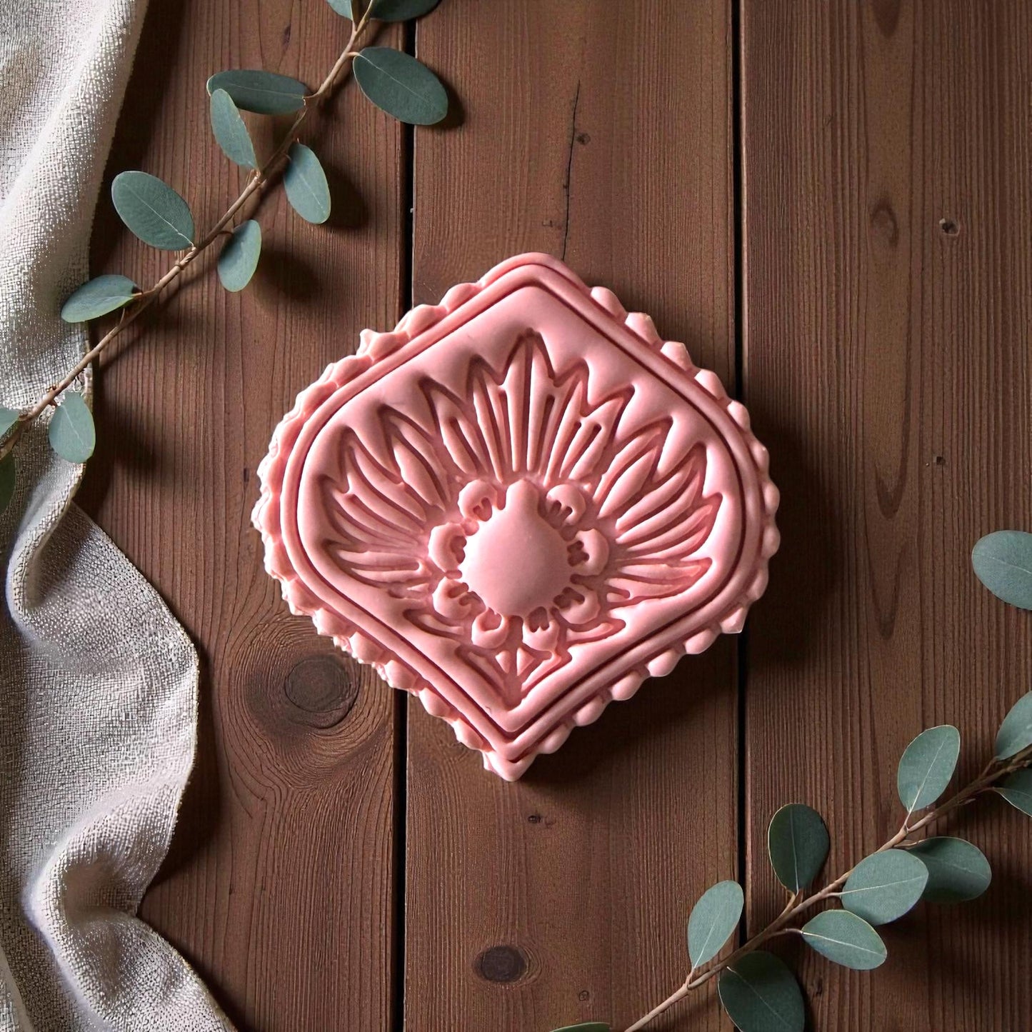 Pink diamond clay imprint on wood with eucalyptus and linen fabric