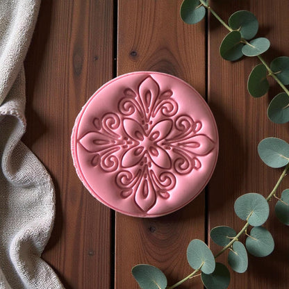 Close-up of round pink floral clay imprint on wooden background with eucalyptus