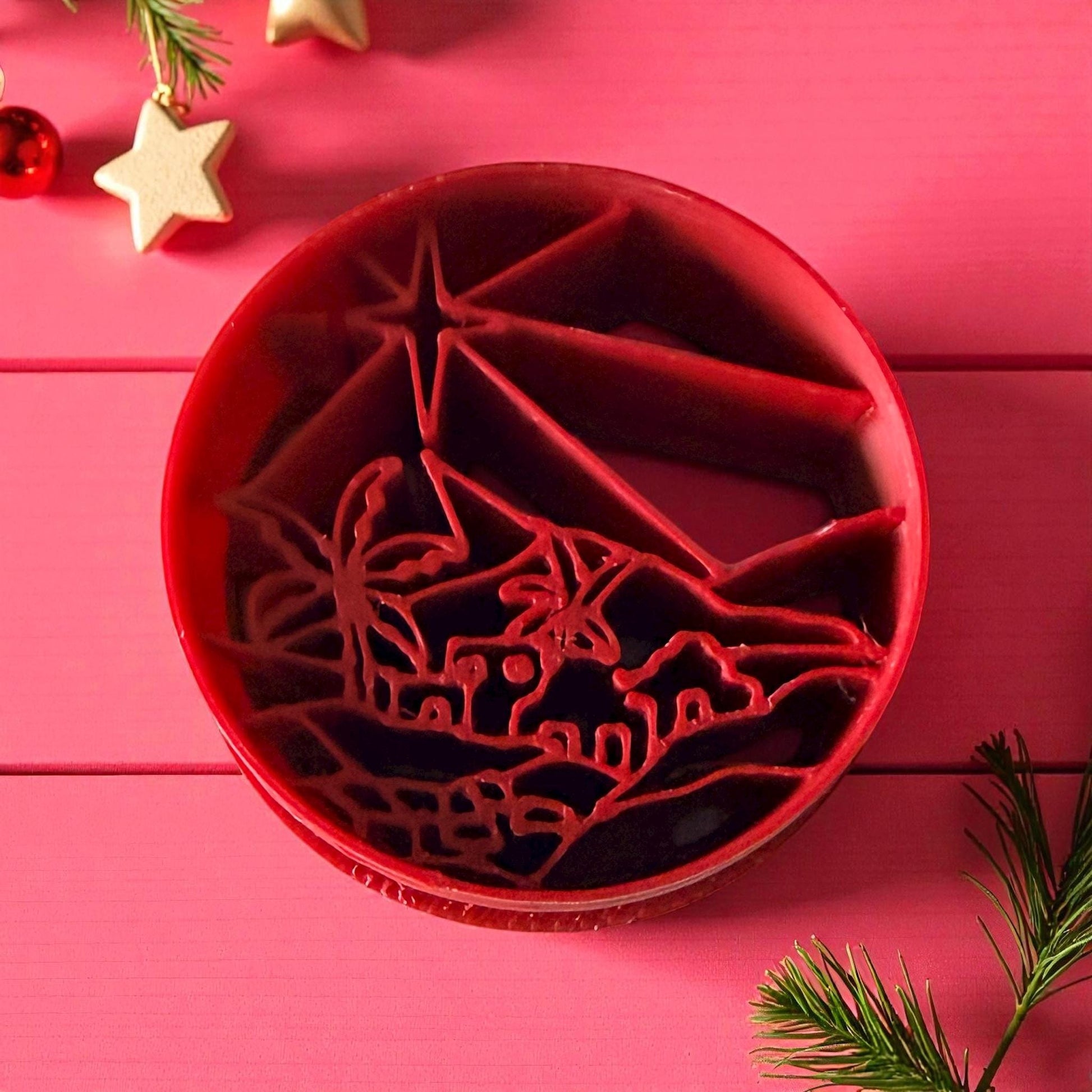 Detailed red Bethlehem town polymer clay cutter surrounded by pine branches
