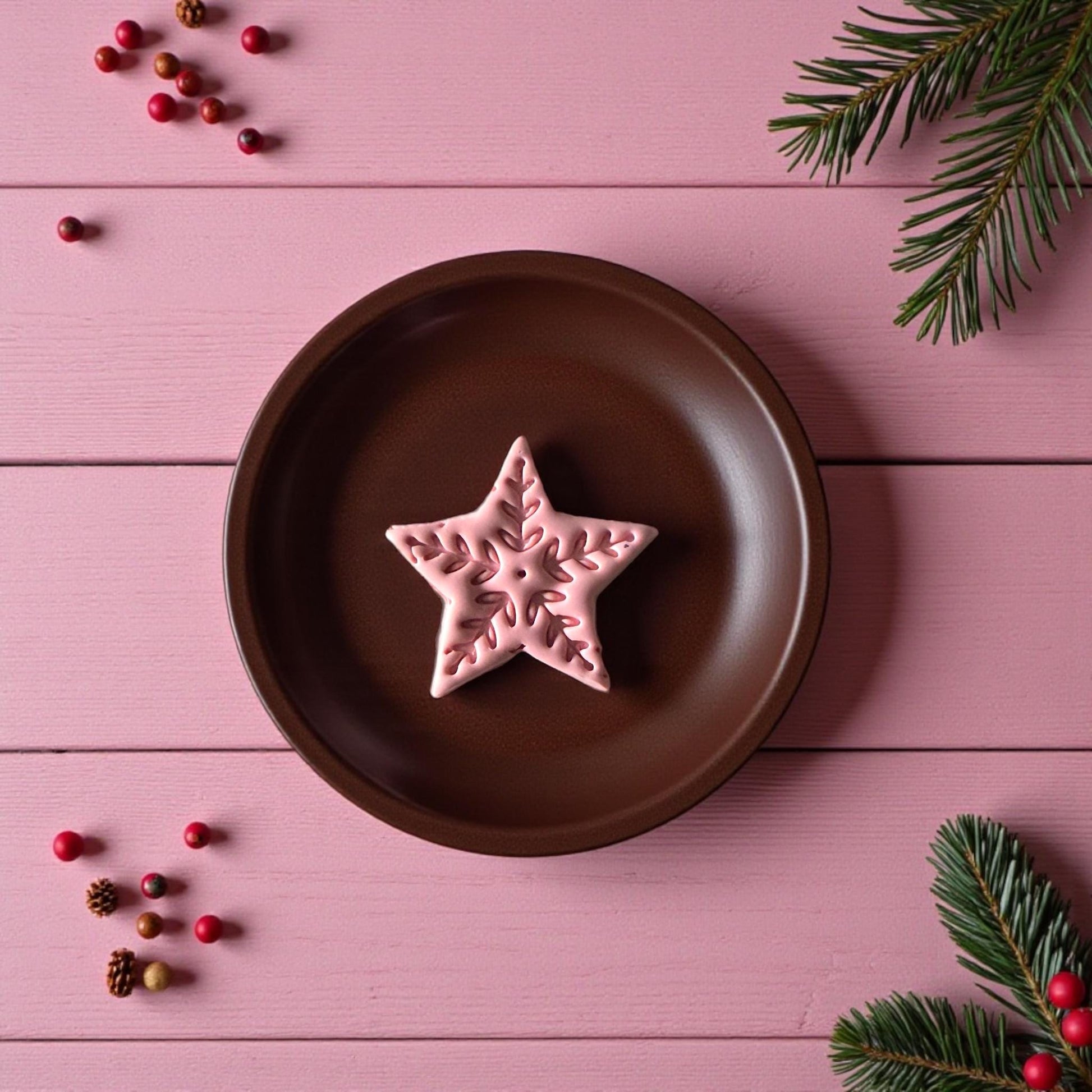 Pink Nordic-style star clay imprint on brown plate with festive pine accents
