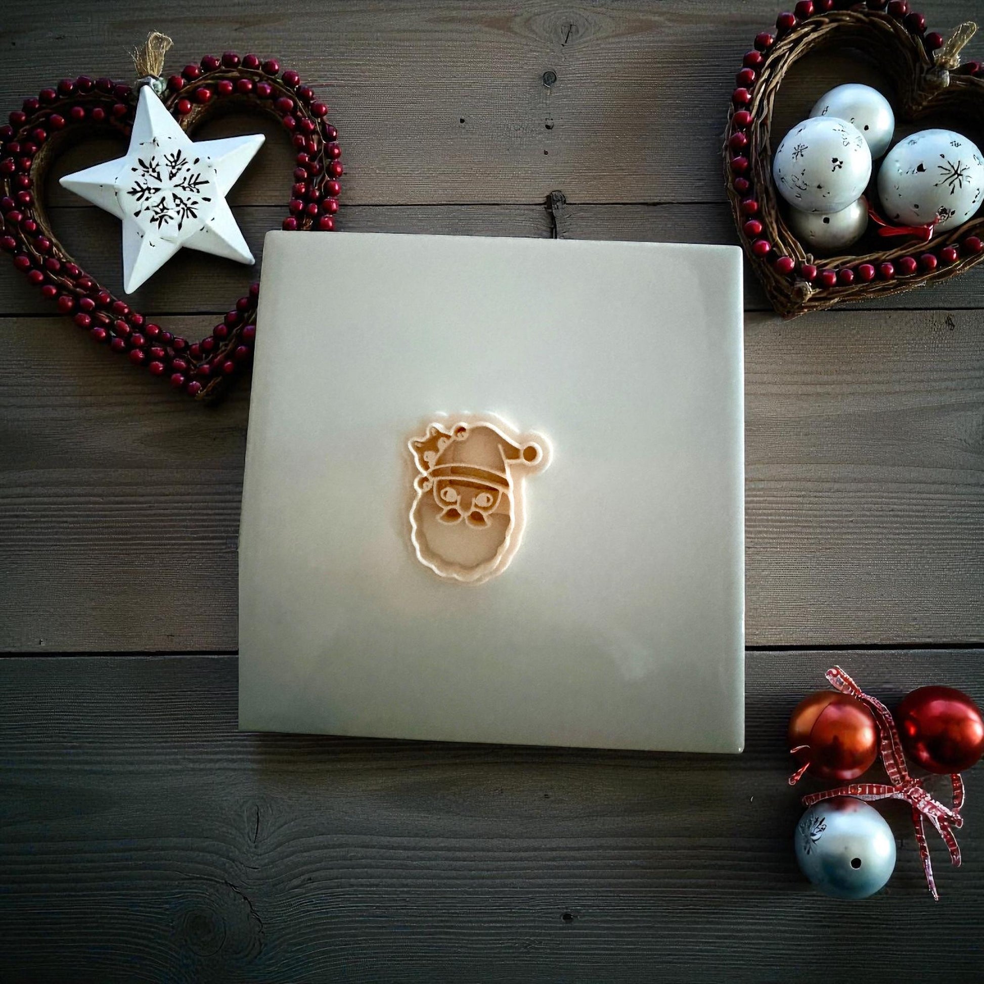 Santa cat polymer clay imprint and cutter displayed on white tile with Christmas ornaments