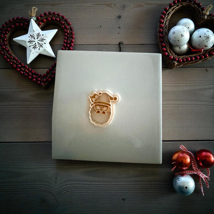 Santa cat polymer clay imprint and cutter displayed on white tile with Christmas ornaments