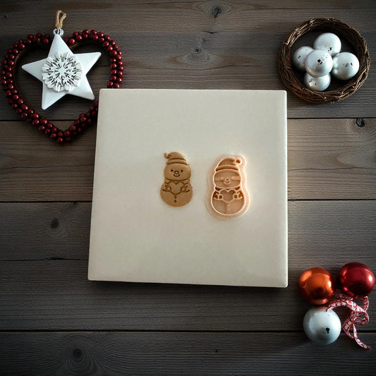 Large snowman clay imprint on red fabric surrounded by gold ornaments and lights