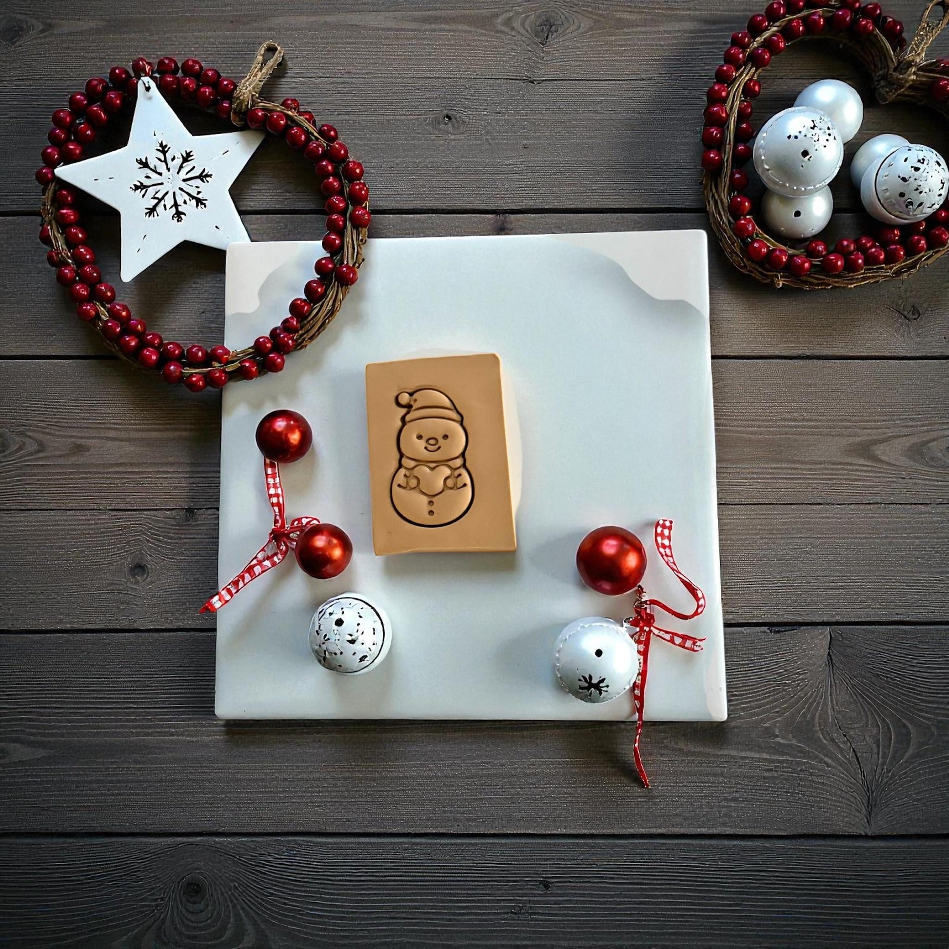 Snowman holding a heart clay imprint on wood background with Christmas decor