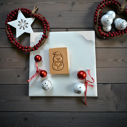 Snowman holding a heart clay imprint on wood background with Christmas decor