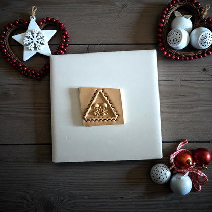 Triangle jingle bell clay imprint with bow detail on wood background with ornaments
