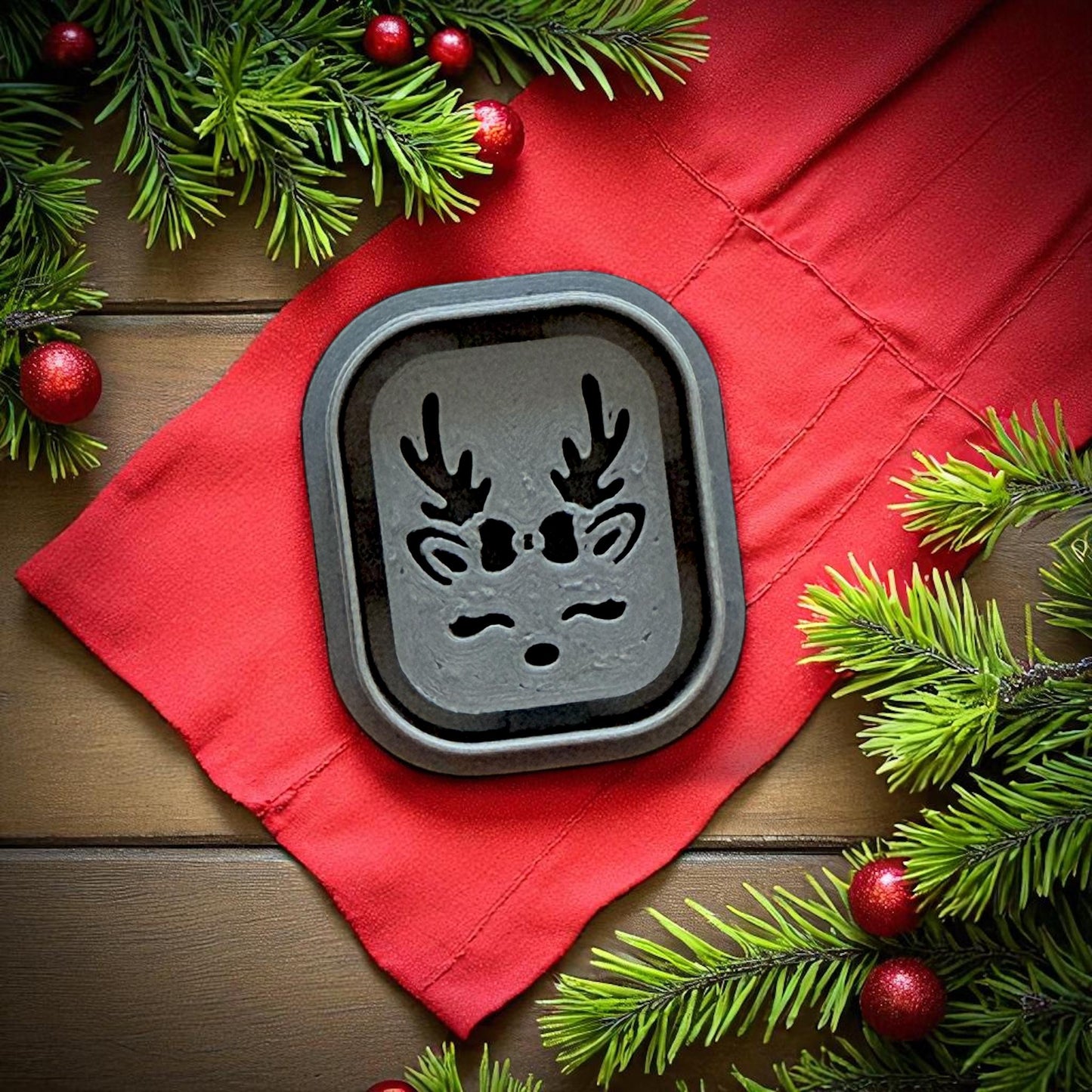 Reindeer polymer clay cutter on red cloth with pine branches and ornaments