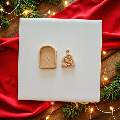 Nativity clay shape with star and Holy Family design on red napkin with pine branches