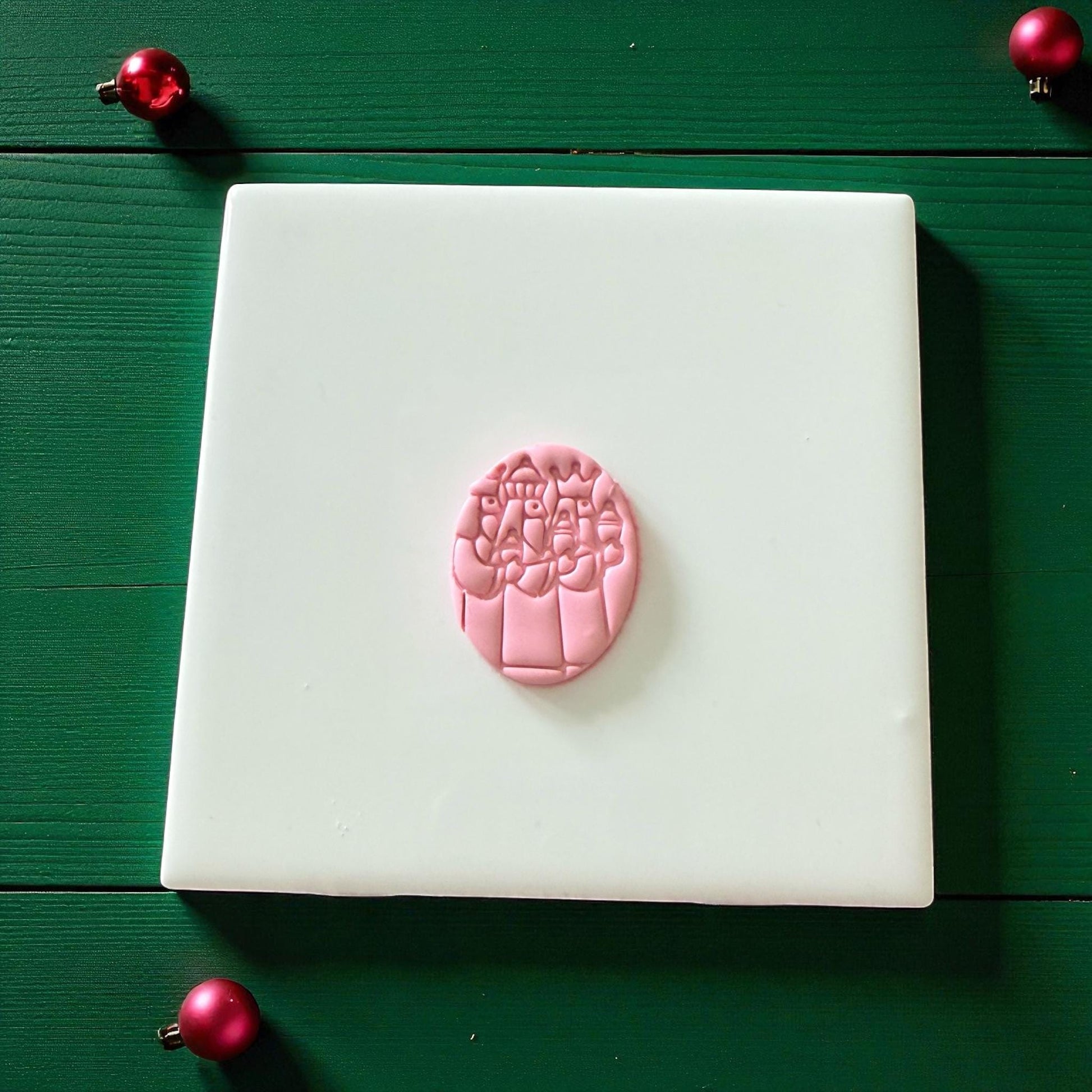 Pink Three Kings clay imprint on white tile with red ornaments