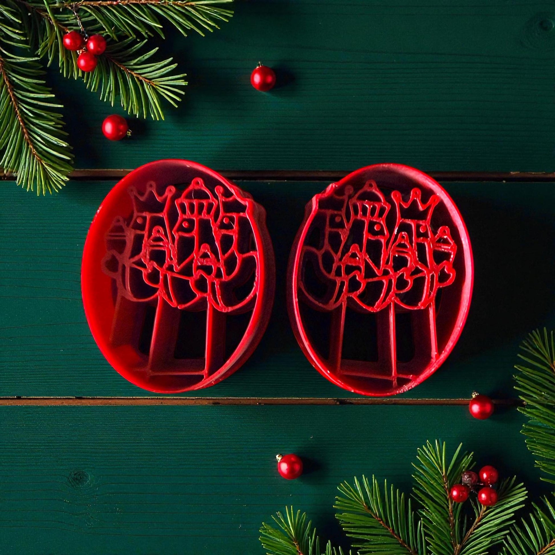 Pair of red Three Kings clay cutters on green background with Christmas accents