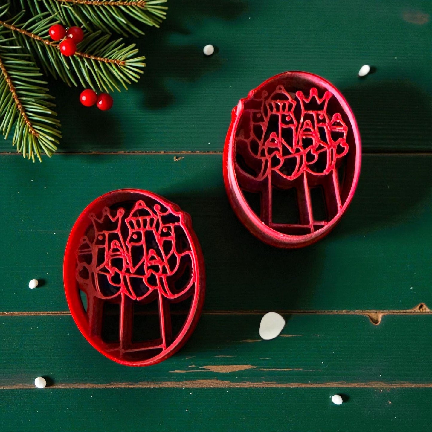 Two red Three Kings cutters on green background with pine branches